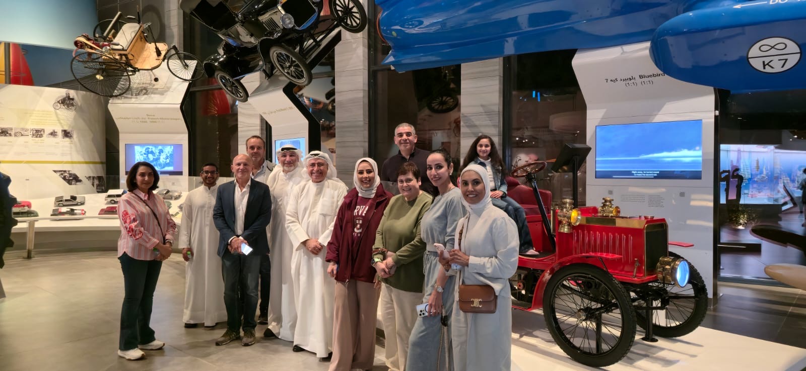 group posing in front of museum car